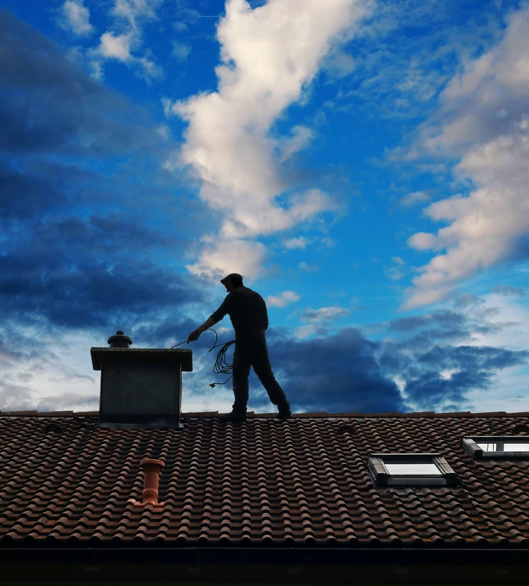 kominiarz na dachu i niebieskie niebo